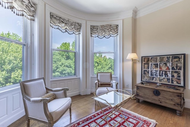 sitting room with wood-type flooring, ornamental molding, and a wealth of natural light