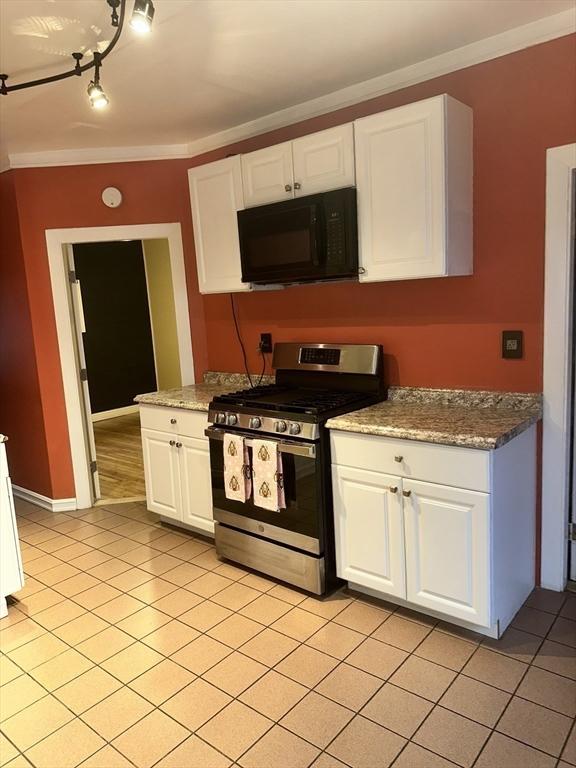 kitchen featuring white cabinets, stainless steel gas stove, light stone counters, and crown molding