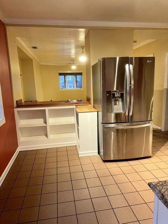 kitchen with stainless steel fridge, crown molding, and light tile patterned flooring