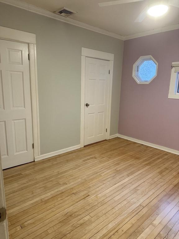 spare room with light hardwood / wood-style floors and crown molding