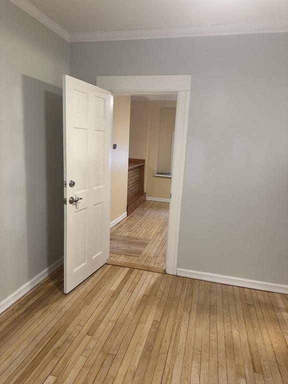 unfurnished room featuring ornamental molding and light wood-type flooring