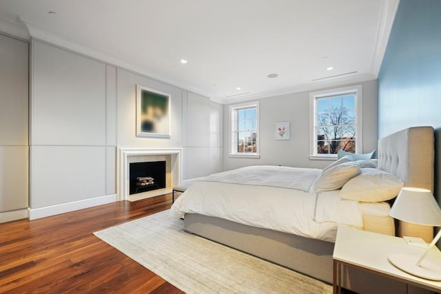 bedroom featuring recessed lighting, a fireplace, crown molding, and wood finished floors