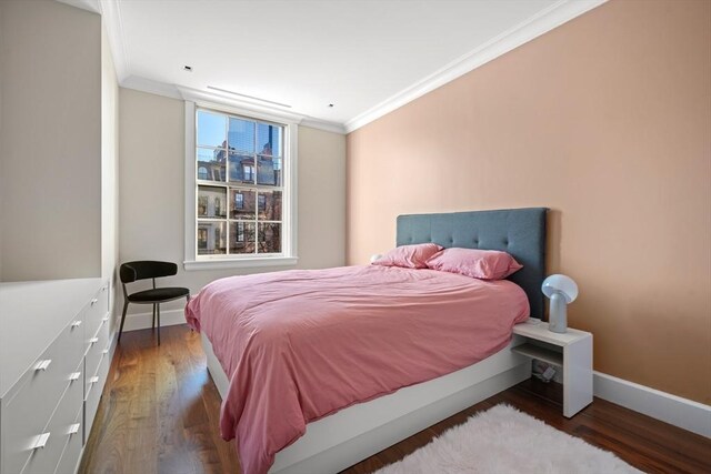 bedroom with wood finished floors, baseboards, and ornamental molding