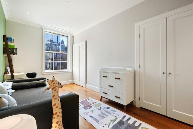 bedroom featuring wood finished floors, baseboards, and ornamental molding