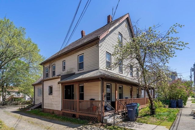 view of front facade with covered porch and a chimney
