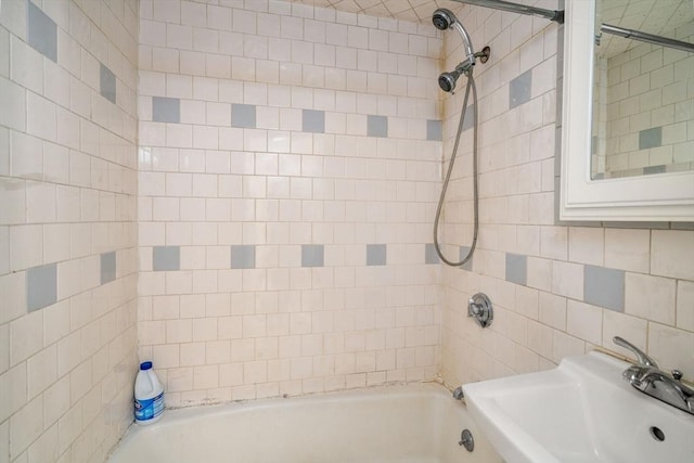 bathroom featuring a sink, washtub / shower combination, and tile walls