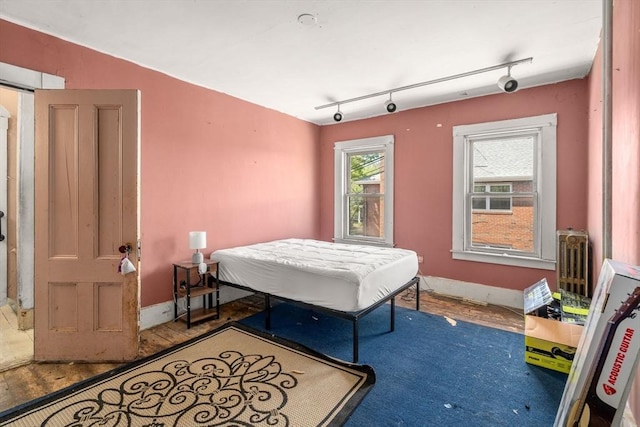 bedroom featuring baseboards, rail lighting, and wood finished floors