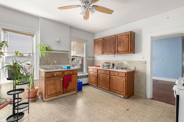kitchen with a sink, radiator, stove, and brown cabinets