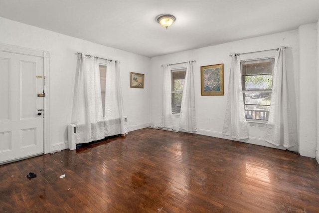 unfurnished room featuring baseboards, wood-type flooring, and a wealth of natural light