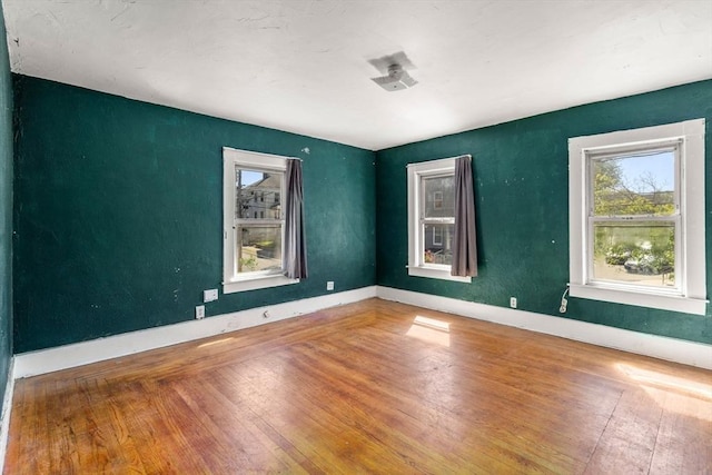 empty room with wood-type flooring and baseboards