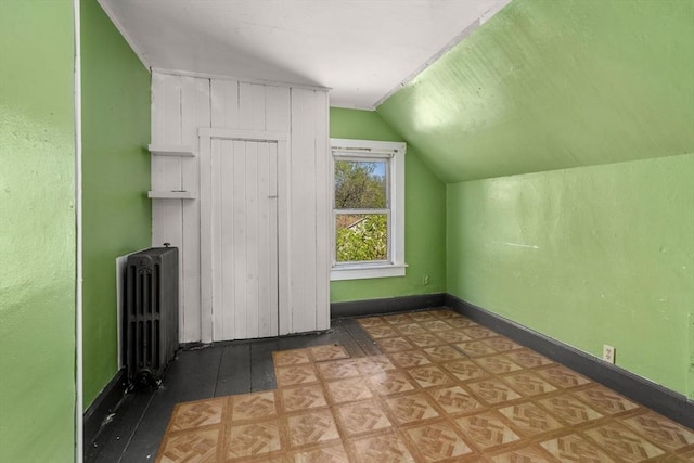 additional living space featuring radiator heating unit, baseboards, wood finished floors, and lofted ceiling