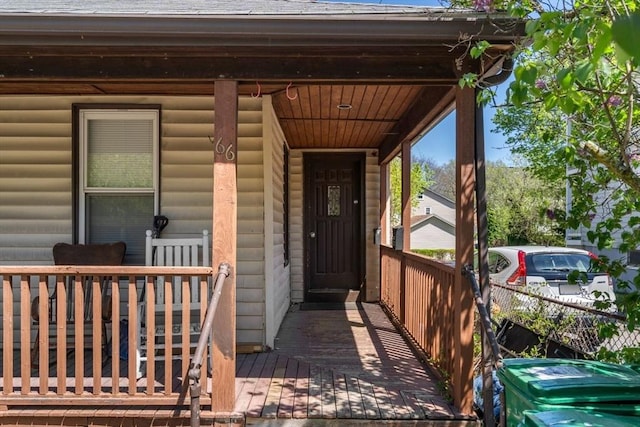 entrance to property featuring roof with shingles and a porch