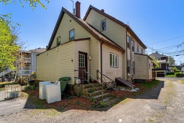 rear view of house with a chimney and entry steps