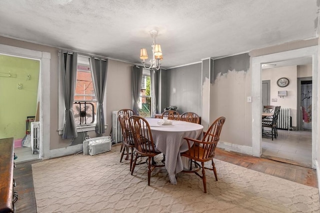 dining space with baseboards, a textured ceiling, a notable chandelier, and hardwood / wood-style floors