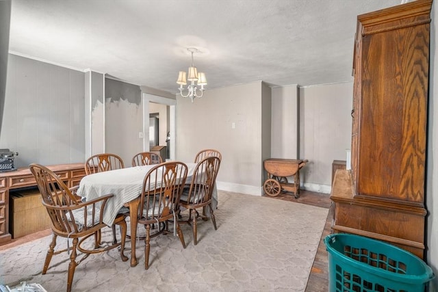 dining space featuring an inviting chandelier, baseboards, light wood finished floors, and a textured ceiling