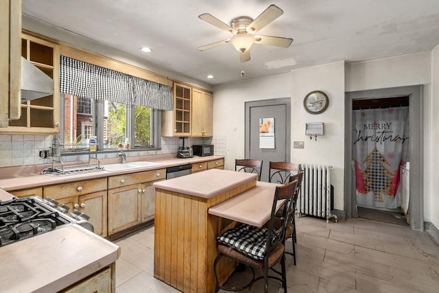 kitchen featuring a sink, light brown cabinets, light countertops, radiator heating unit, and tasteful backsplash