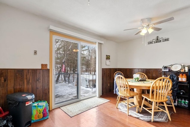 dining room with ceiling fan, wood-type flooring, and wooden walls