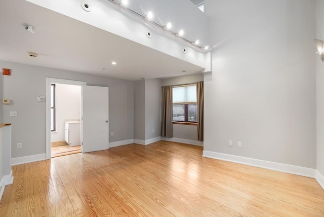 unfurnished room with light wood-style floors, baseboards, and washer / clothes dryer