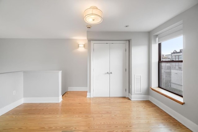 unfurnished bedroom with visible vents, light wood-style floors, baseboards, and a closet