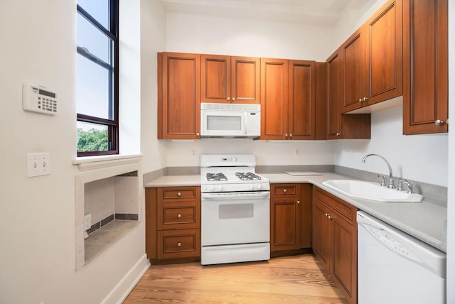 kitchen featuring a sink, light countertops, white appliances, and light wood-style flooring
