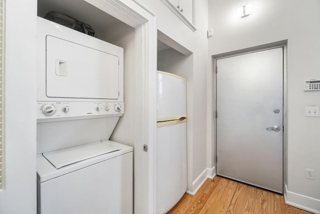 washroom with baseboards, laundry area, light wood finished floors, and stacked washer and clothes dryer