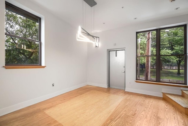 unfurnished room featuring baseboards, plenty of natural light, and light wood-type flooring