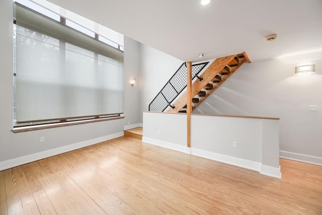 unfurnished living room with light wood-style floors, baseboards, recessed lighting, and stairs