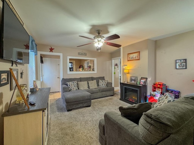 carpeted living area with ceiling fan and a glass covered fireplace