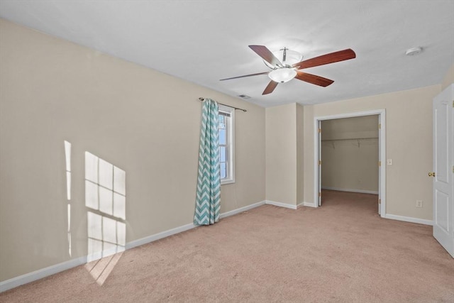 unfurnished bedroom featuring carpet, baseboards, a spacious closet, a ceiling fan, and a closet