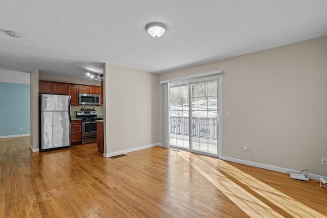 kitchen with stainless steel appliances, light wood-type flooring, and baseboards