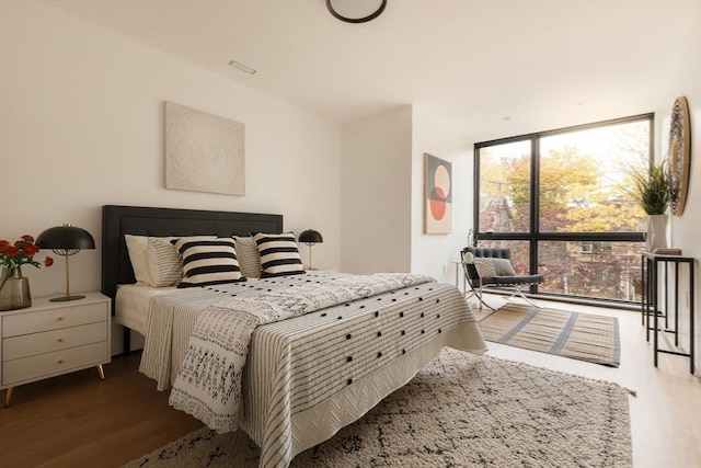 bedroom with floor to ceiling windows and dark wood-type flooring