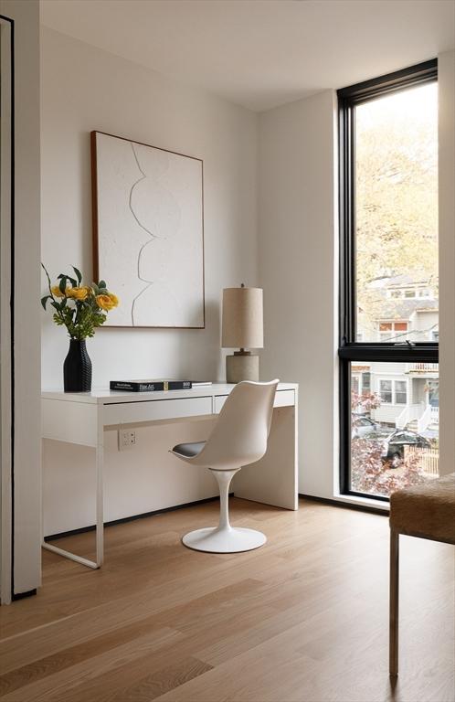 home office with expansive windows and light hardwood / wood-style flooring