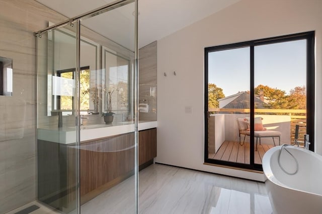 bathroom with a washtub, vanity, and vaulted ceiling