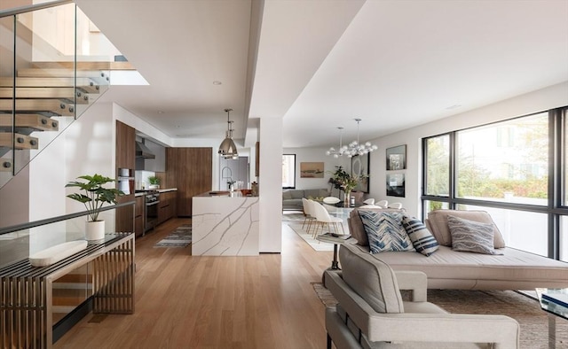 living room featuring sink, a chandelier, and light wood-type flooring