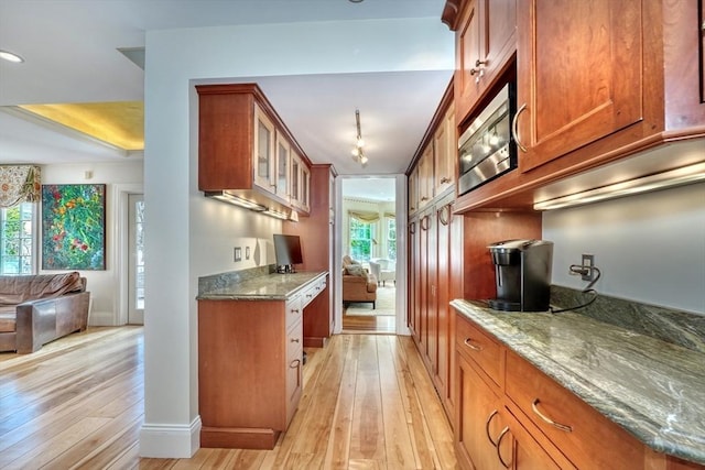 10 Sheffield Rd, Winchester, MA 01890 - kitchen featuring brown cabinetry, light wood-style floors, stainless steel microwave, and stone countertops