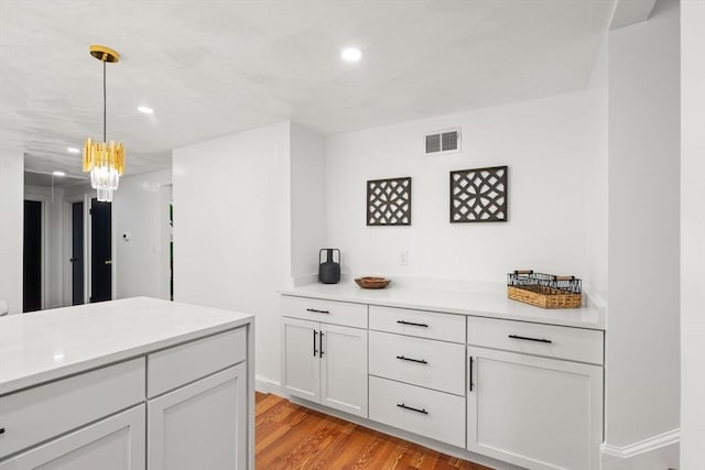 379 Dedham Ave, Needham, MA 02492 - kitchen featuring light countertops, recessed lighting, hanging light fixtures, light wood-type flooring, and a chandelier