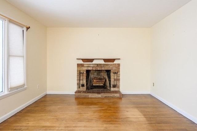 unfurnished living room with a fireplace, baseboards, and wood finished floors