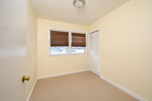 unfurnished bedroom with baseboards, a closet, and light colored carpet