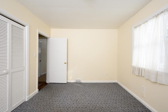 unfurnished bedroom with carpet floors, baseboards, multiple windows, and visible vents