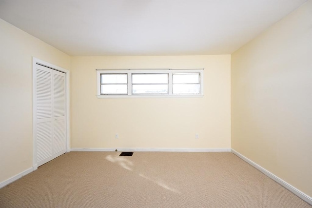 unfurnished bedroom featuring light carpet, visible vents, baseboards, and a closet