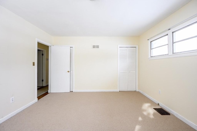 empty room with carpet, visible vents, and baseboards