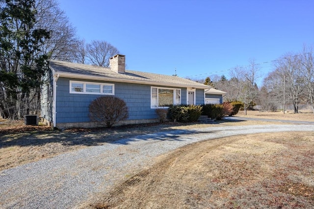 single story home featuring a garage, a chimney, and central air condition unit