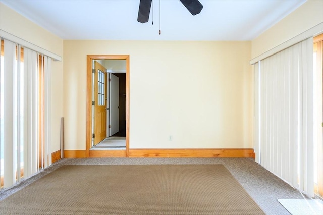 carpeted empty room featuring ceiling fan and baseboards