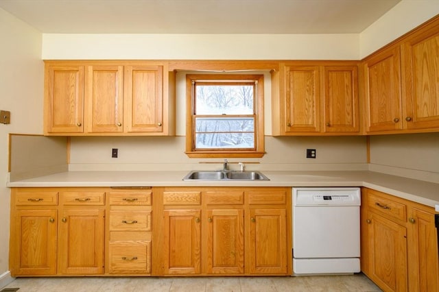 kitchen with brown cabinets, light countertops, white dishwasher, and a sink