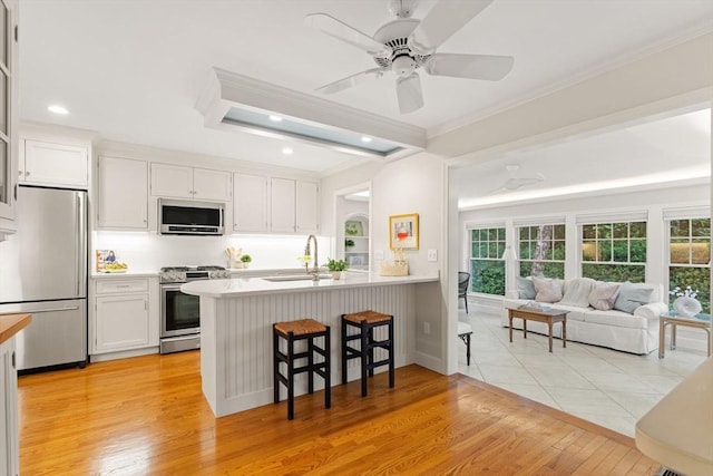 28 Pleasant View Rd, Arlington, MA 02476 - kitchen with stainless steel appliances, a breakfast bar, ornamental molding, white cabinets, and open floor plan