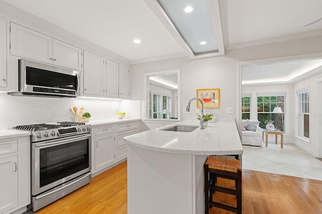 28 Pleasant View Rd, Arlington, MA 02476 - kitchen featuring appliances with stainless steel finishes, a peninsula, a kitchen bar, white cabinetry, and recessed lighting