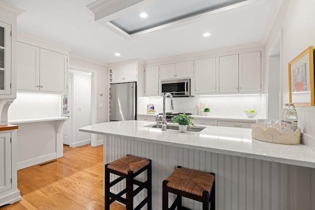 28 Pleasant View Rd, Arlington, MA 02476 - kitchen with stainless steel appliances, white cabinetry, a breakfast bar area, light wood-style floors, and a peninsula