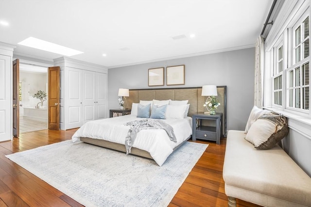 bedroom with ensuite bath, crown molding, a closet, and hardwood / wood-style flooring