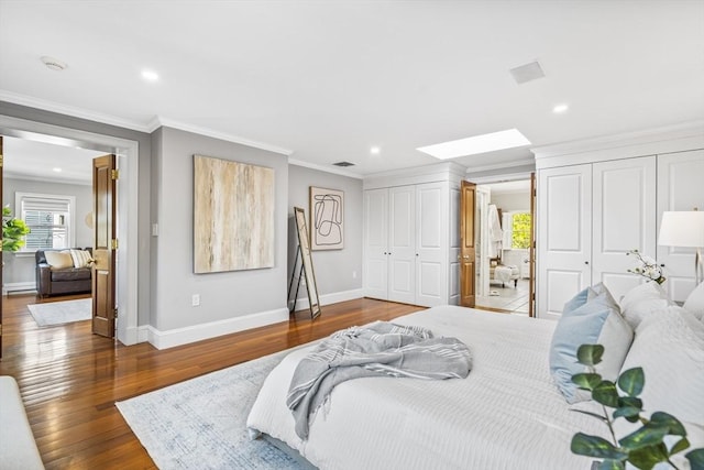 bedroom with dark hardwood / wood-style flooring, a skylight, a baseboard radiator, and crown molding