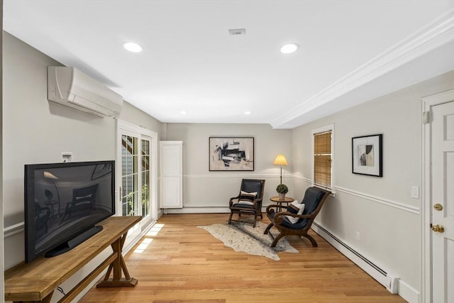 living area featuring light hardwood / wood-style floors, a wall unit AC, and a baseboard radiator